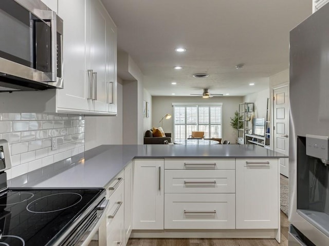 1110 Sherwood Ln Unit 223, Nichols Hills, OK 73116 - kitchen with appliances with stainless steel finishes, a peninsula, white cabinetry, recessed lighting, and decorative backsplash