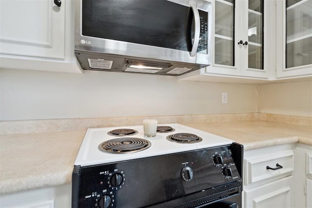 3119 W Wilshire Blvd, Oklahoma City, OK 73116 - kitchen featuring electric range oven, stainless steel microwave, white cabinets, glass insert cabinets, and light countertops