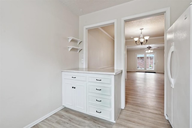 3119 W Wilshire Blvd, Oklahoma City, OK 73116 - hallway with a chandelier, light wood-type flooring, a textured ceiling, baseboards, and ornamental molding