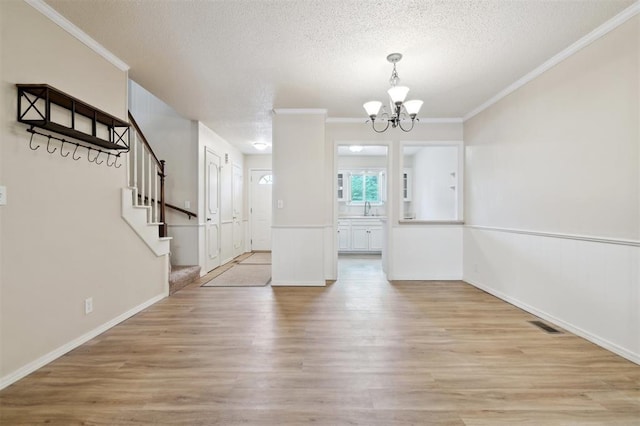 3119 W Wilshire Blvd, Oklahoma City, OK 73116 - unfurnished dining area with a chandelier, a textured ceiling, light wood-style floors, crown molding, and a sink