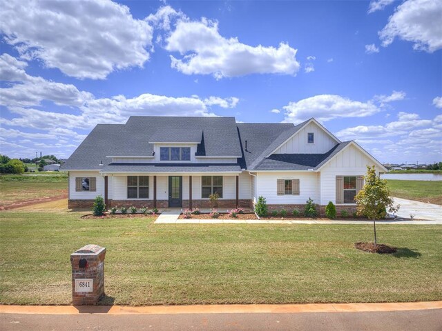 6841 Lake View Ct, Cashion, OK 73016 - view of front of house featuring board and batten siding, a front yard, stone siding, and a porch
