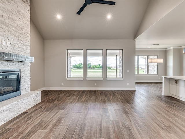 6841 Lake View Ct, Cashion, OK 73016 - unfurnished living room featuring ceiling fan, a stone fireplace, high vaulted ceiling, dark wood-style flooring, and baseboards