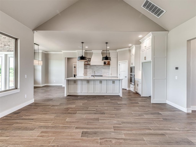 6841 Lake View Ct, Cashion, OK 73016 - kitchen featuring premium range hood, backsplash, white cabinets, a sink, and light countertops