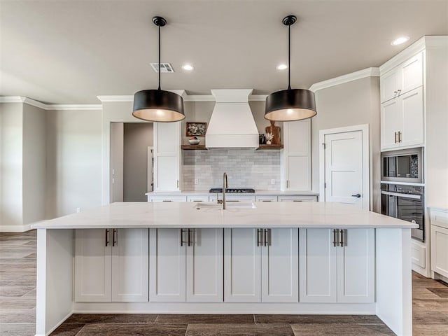 6841 Lake View Ct, Cashion, OK 73016 - kitchen with appliances with stainless steel finishes, premium range hood, ornamental molding, a large island with sink, and tasteful backsplash