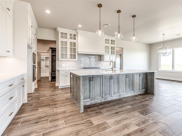 6860 Lake View Ct, Cashion, OK 73016 - kitchen featuring wood tiled floors, light countertops, white cabinets, a spacious island, and recessed lighting