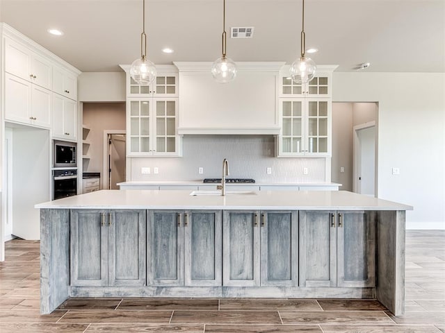6860 Lake View Ct, Cashion, OK 73016 - kitchen with a large island with sink, appliances with stainless steel finishes, white cabinets, backsplash, and a sink