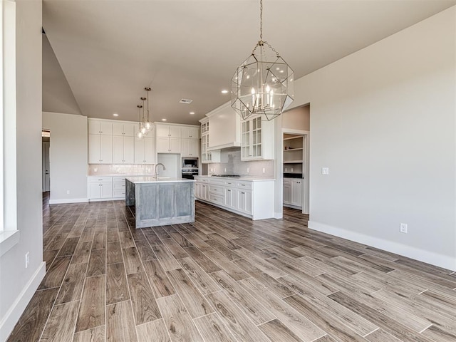 6860 Lake View Ct, Cashion, OK 73016 - kitchen featuring a chandelier, wood finished floors, baseboards, an island with sink, and recessed lighting
