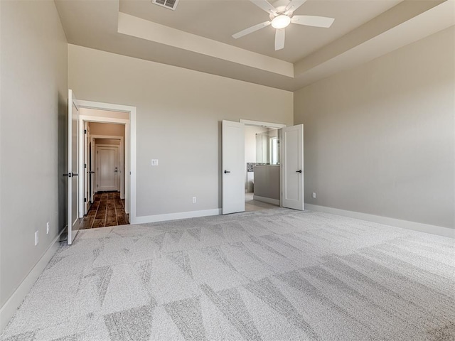 6860 Lake View Ct, Cashion, OK 73016 - unfurnished bedroom with carpet floors, a tray ceiling, baseboards, and a ceiling fan