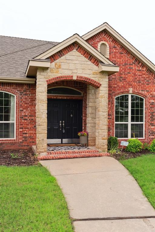 607 Pool Pl, Shawnee, OK 74801 - view of exterior entry featuring brick siding, a shingled roof, and stone siding