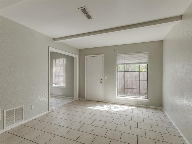 2720 SW 74th St Unit 6, Oklahoma City, OK 73159 - empty room with a textured wall, plenty of natural light, beamed ceiling, baseboards, and light tile patterned floors