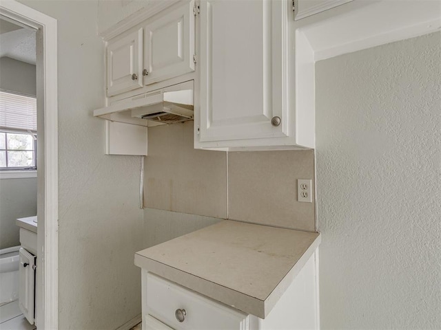 2720 SW 74th St Unit 6, Oklahoma City, OK 73159 - kitchen with light countertops, under cabinet range hood, white cabinets, and a textured wall