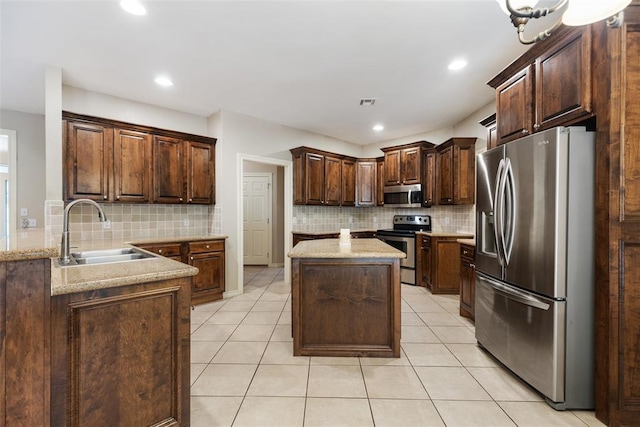 10650 Hunters Pointe, Edmond, OK 73034 - kitchen with appliances with stainless steel finishes, a sink, backsplash, light tile patterned flooring, and a kitchen island