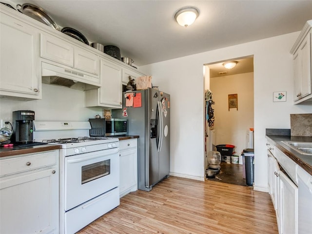 4900 S Post Rd, Oklahoma City, OK 73150 - kitchen featuring stainless steel appliances, under cabinet range hood, dark countertops, and light wood finished floors