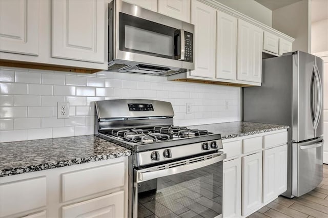 1330 Round Leaf Rd, Edmond, OK 73034 - kitchen with appliances with stainless steel finishes, white cabinetry, decorative backsplash, and dark stone counters