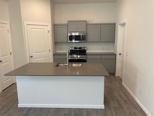 3008 NW 196th Pl, Edmond, OK 73012 - kitchen featuring appliances with stainless steel finishes, gray cabinets, a sink, tasteful backsplash, and dark stone counters