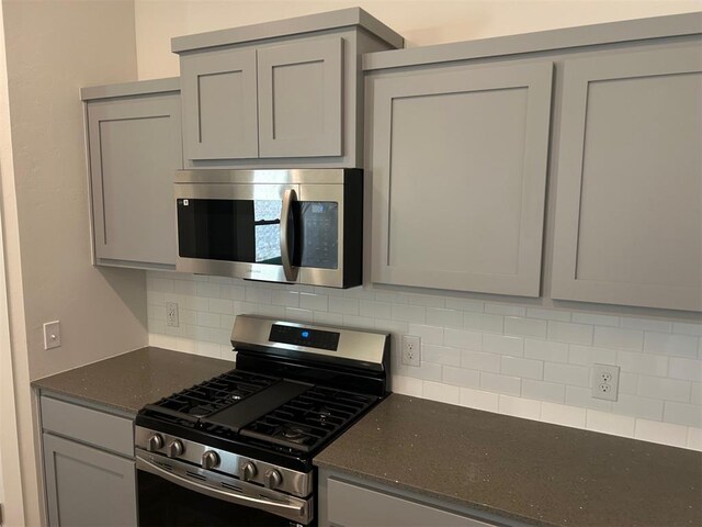 3008 NW 196th Pl, Edmond, OK 73012 - kitchen with appliances with stainless steel finishes, gray cabinetry, decorative backsplash, and dark stone countertops