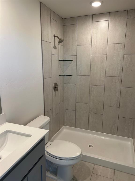 3008 NW 196th Pl, Edmond, OK 73012 - bathroom with vanity, tiled shower, toilet, and tile patterned floors