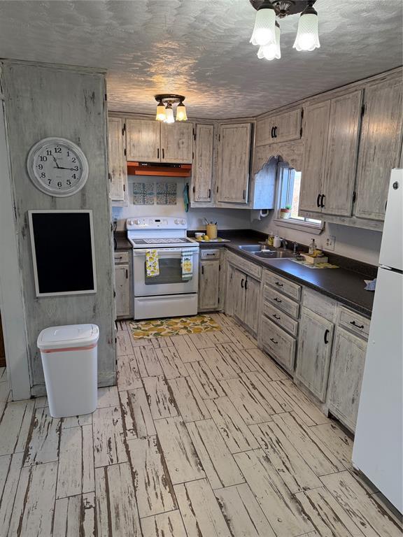 134 Wood St, Fort Cobb, OK 73038 - kitchen featuring white appliances, dark countertops, a sink, and light wood finished floors