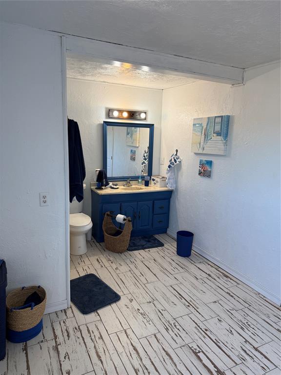 134 Wood St, Fort Cobb, OK 73038 - bathroom featuring vanity, toilet, wood finished floors, and baseboards