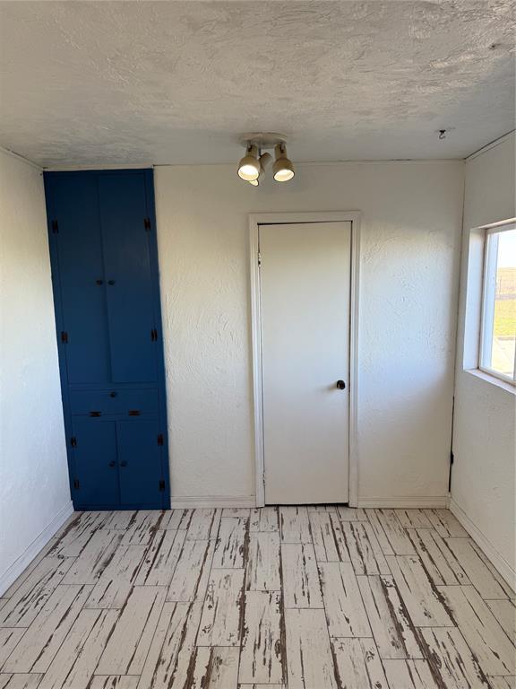 134 Wood St, Fort Cobb, OK 73038 - empty room with light wood finished floors, a textured ceiling, and baseboards