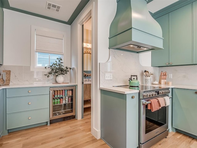 51 Lower Green Way, Carlton Landing, OK 74432 - kitchen featuring stainless steel electric stove, custom exhaust hood, green cabinets, wine cooler, and tasteful backsplash