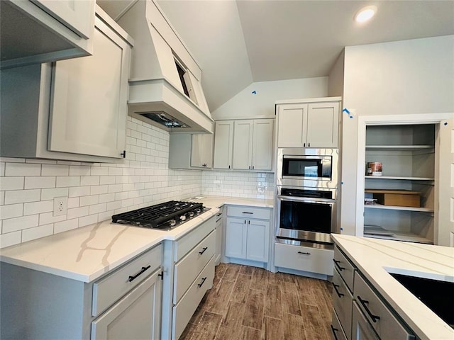 913 SW 141st St, Oklahoma City, OK 73170 - kitchen with appliances with stainless steel finishes, lofted ceiling, custom exhaust hood, dark wood-style floors, and light stone counters