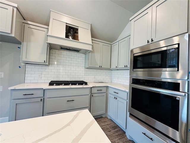 913 SW 141st St, Oklahoma City, OK 73170 - kitchen with appliances with stainless steel finishes, tasteful backsplash, dark wood-style flooring, vaulted ceiling, and light stone countertops