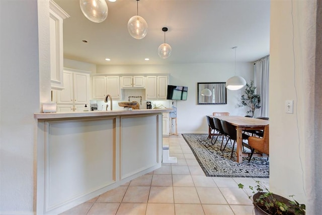 608 Shadow View Ct, Norman, OK 73072 - kitchen with light tile patterned floors, a peninsula, decorative light fixtures, white cabinets, and recessed lighting