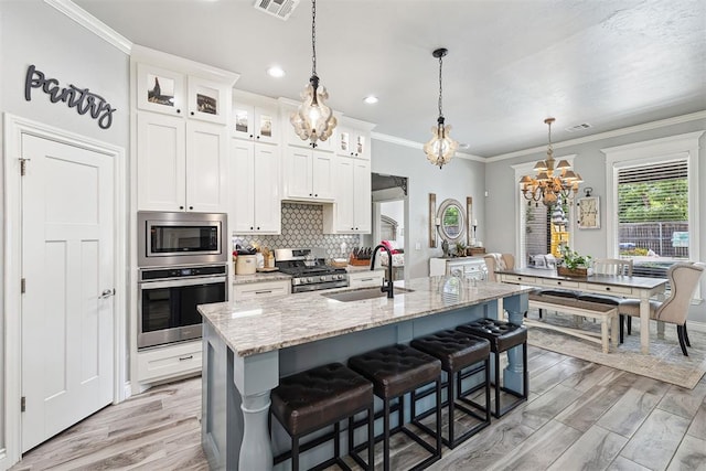 4813 Hambletonian Ln, Mustang, OK 73064 - kitchen with stainless steel appliances, a chandelier, a sink, a center island with sink, and light stone counters