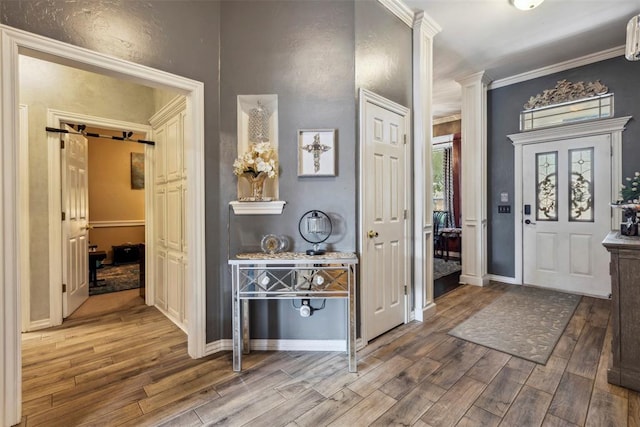 704 N Geronimo Way, Mustang, OK 73064 - entrance foyer featuring wood finished floors, ornate columns, crown molding, and a barn door