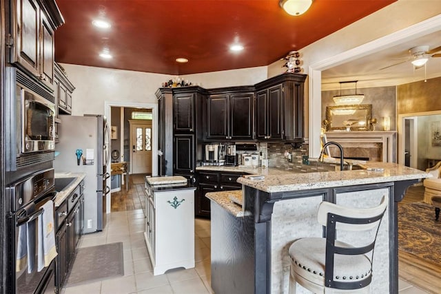 704 N Geronimo Way, Mustang, OK 73064 - kitchen with appliances with stainless steel finishes, a kitchen island, light tile patterned flooring, and a kitchen breakfast bar