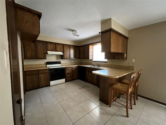 3014 S Mission St, Anadarko, OK 73005 - kitchen with electric stove, a peninsula, light countertops, light tile patterned floors, and under cabinet range hood