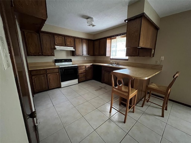 3014 S Mission St, Anadarko, OK 73005 - kitchen featuring electric stove, under cabinet range hood, light countertops, a textured ceiling, and light tile patterned floors