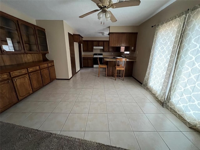 3014 S Mission St, Anadarko, OK 73005 - kitchen featuring electric range, ceiling fan, a kitchen breakfast bar, a peninsula, and light tile patterned floors