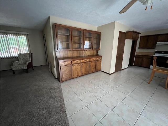 3014 S Mission St, Anadarko, OK 73005 - kitchen featuring stove, a ceiling fan, glass insert cabinets, light tile patterned floors, and dark countertops