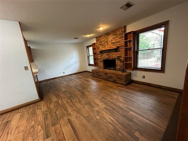 2308 Lynn Ln, Weatherford, OK 73096 - unfurnished living room with wood-type flooring, baseboards, and a brick fireplace