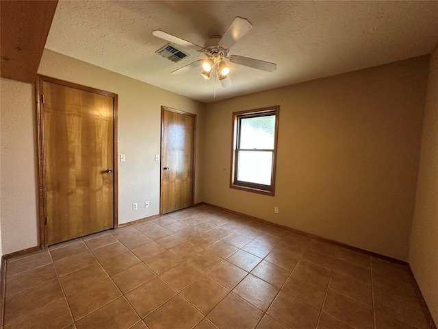 2308 Lynn Ln, Weatherford, OK 73096 - unfurnished bedroom with tile patterned floors, a textured ceiling, baseboards, and a ceiling fan