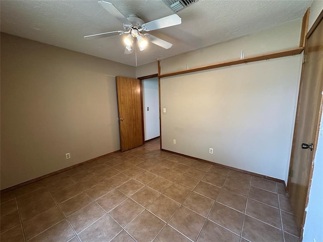 2308 Lynn Ln, Weatherford, OK 73096 - unfurnished bedroom featuring tile patterned flooring, baseboards, a ceiling fan, and a textured ceiling