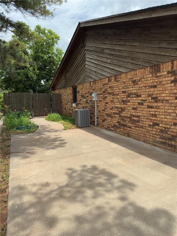 2308 Lynn Ln, Weatherford, OK 73096 - view of side of property with cooling unit, a patio, and brick siding