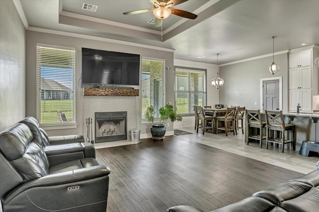 2383 Fox Ln, Blanchard, OK 73010 - living area with a ceiling fan, a tray ceiling, a fireplace, wood finished floors, and crown molding