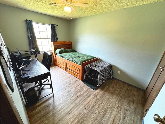 900 Hairston St, Altus, OK 73521 - bedroom featuring wood finished floors, a ceiling fan, a textured ceiling, a desk, and baseboards