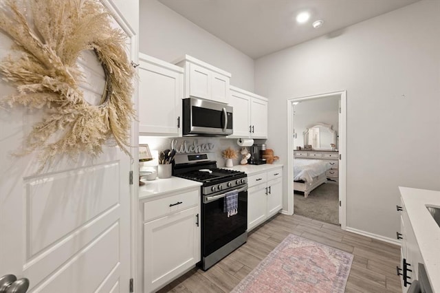 19908 Taggert Dr, Edmond, OK 73012 - kitchen with stainless steel appliances, light countertops, white cabinetry, light wood-style floors, and baseboards