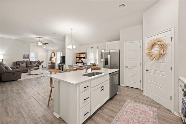 19908 Taggert Dr, Edmond, OK 73012 - kitchen featuring appliances with stainless steel finishes, vaulted ceiling, a sink, a ceiling fan, and white cabinetry