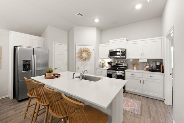 19908 Taggert Dr, Edmond, OK 73012 - kitchen featuring stainless steel appliances, a sink, backsplash, white cabinets, and vaulted ceiling