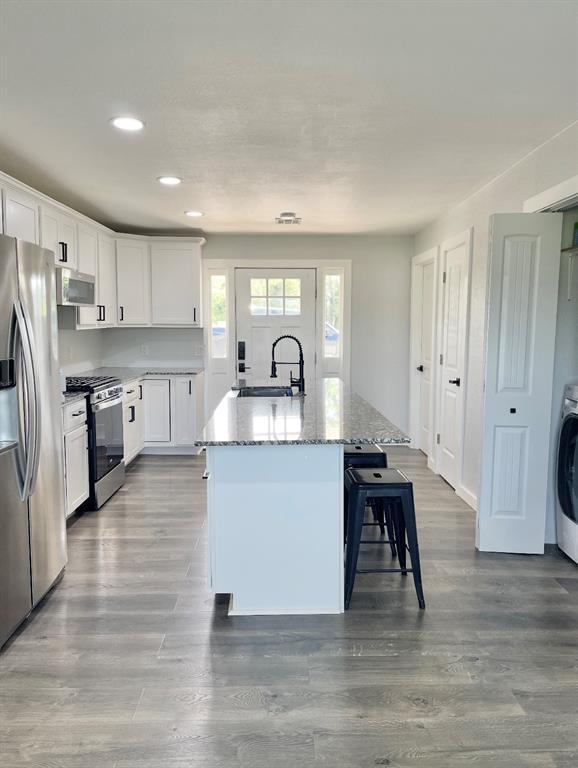 1304 W Walnut St, Tecumseh, OK 74873 - kitchen with stainless steel appliances, recessed lighting, a breakfast bar, light stone counters, and white cabinets
