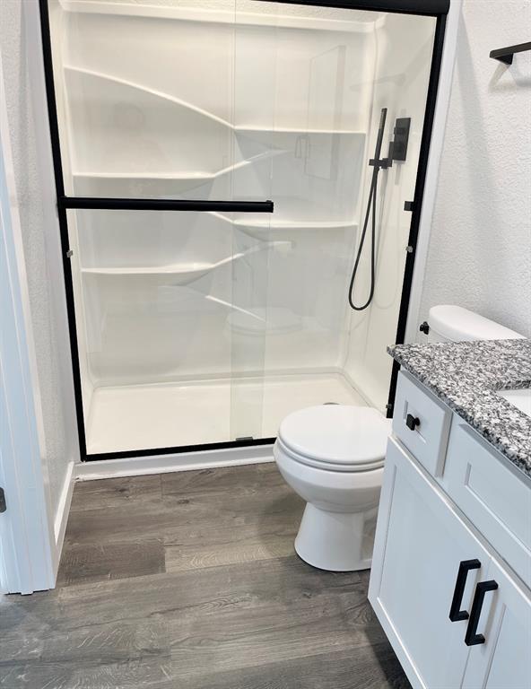 1304 W Walnut St, Tecumseh, OK 74873 - full bathroom with a shower stall, wood finished floors, and vanity