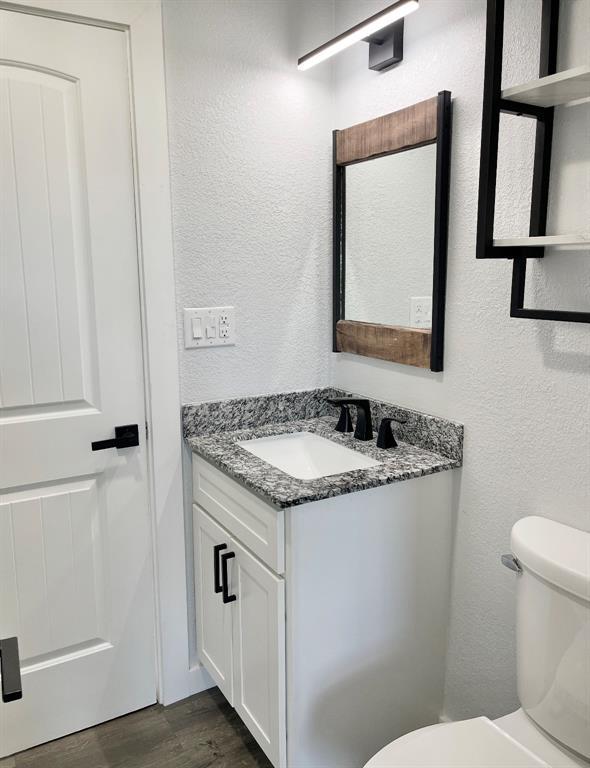 1304 W Walnut St, Tecumseh, OK 74873 - half bath featuring vanity, a textured wall, and wood finished floors