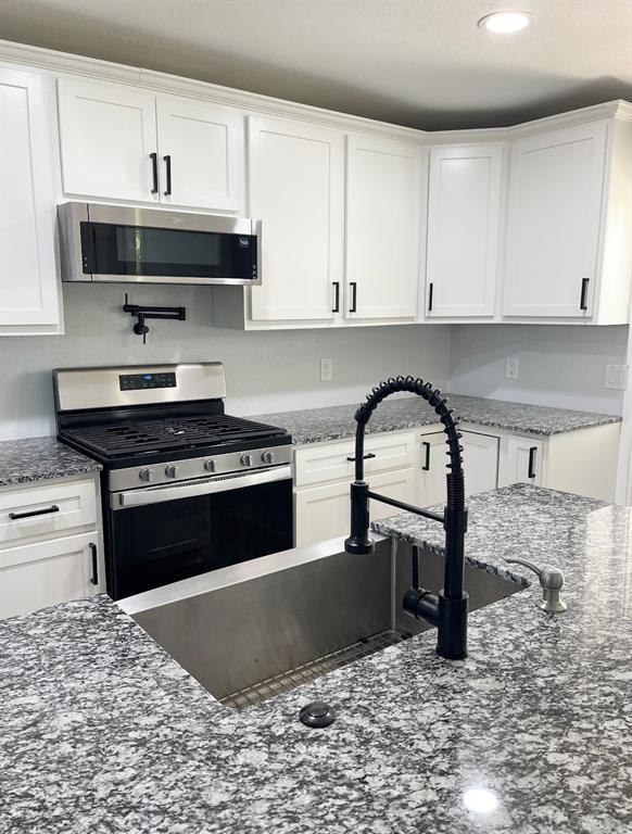 1304 W Walnut St, Tecumseh, OK 74873 - kitchen featuring stainless steel appliances, white cabinetry, dark stone countertops, and recessed lighting