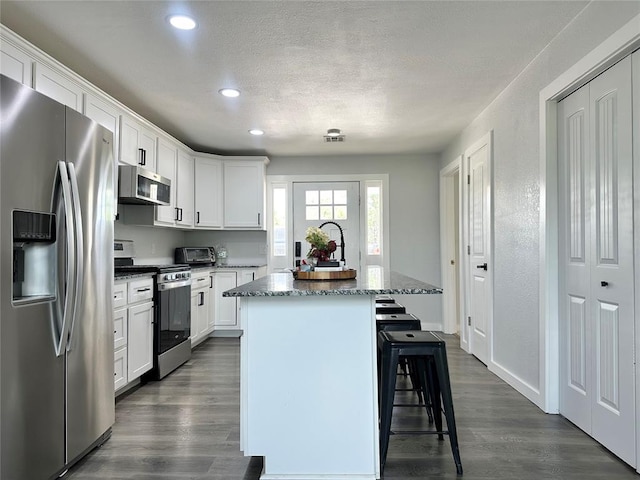1304 W Walnut St, Tecumseh, OK 74873 - kitchen with stainless steel appliances, recessed lighting, a kitchen breakfast bar, dark wood finished floors, and a center island