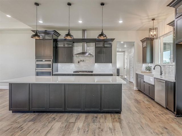 5812 Cimarron Mnr, Guthrie, OK 73044 - kitchen featuring a large island, light wood finished floors, light countertops, backsplash, and wall chimney range hood
